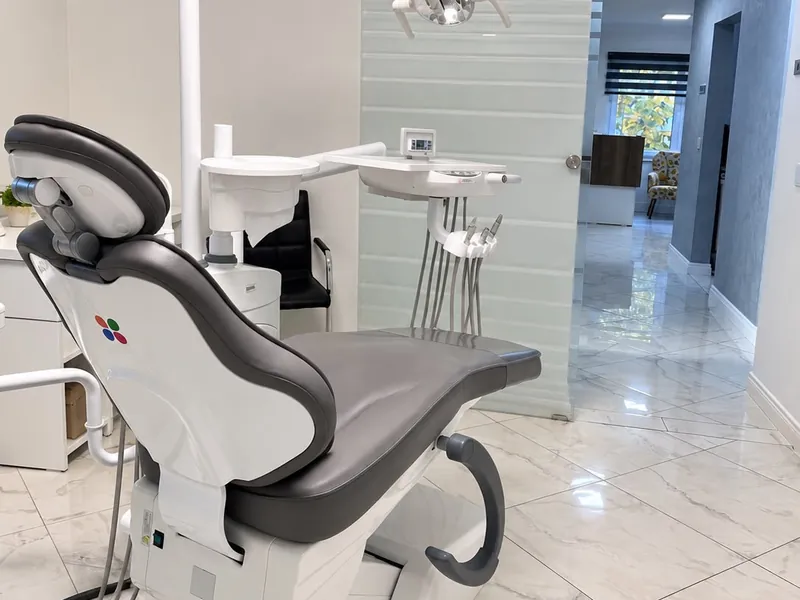 Cabinetul 2: fotoliul stomatologic gri, cu holul clinicii în fundal.
